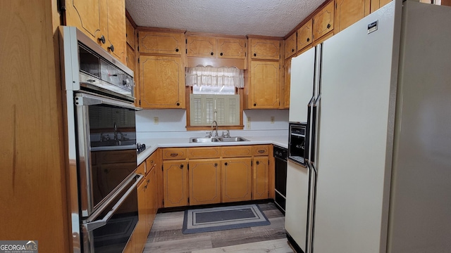 kitchen featuring sink, oven, white fridge with ice dispenser, and a textured ceiling