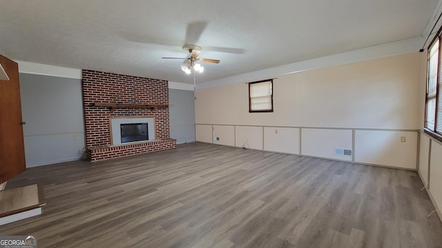 unfurnished living room featuring ceiling fan, a fireplace, and light wood-type flooring