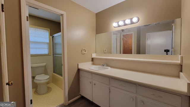 full bathroom featuring toilet, tile walls, vanity, enclosed tub / shower combo, and tile patterned flooring