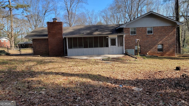 rear view of house with cooling unit, a sunroom, a patio, and a lawn