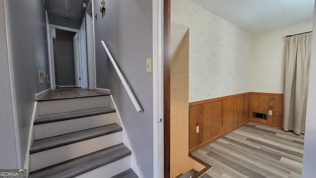 stairs featuring wood-type flooring and wooden walls