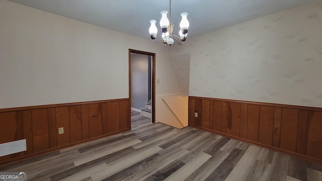 unfurnished room featuring a chandelier and light wood-type flooring