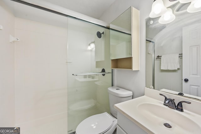 bathroom with vanity, a shower with shower door, and toilet