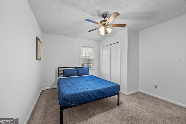 carpeted bedroom with ceiling fan, a textured ceiling, and a closet