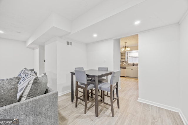 dining space featuring sink, an inviting chandelier, and light hardwood / wood-style flooring