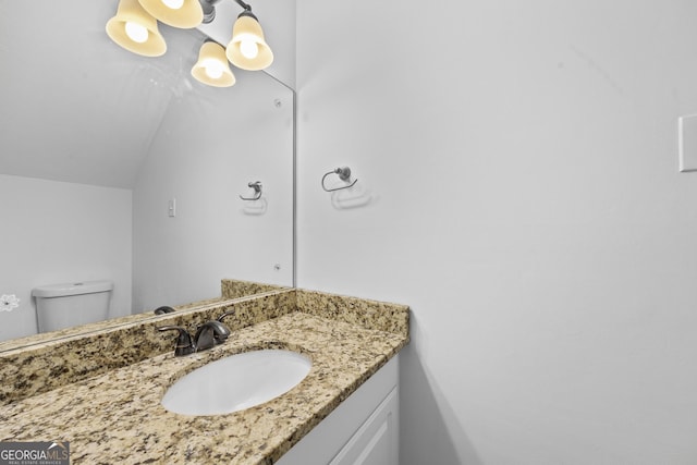 bathroom featuring vanity, lofted ceiling, and toilet