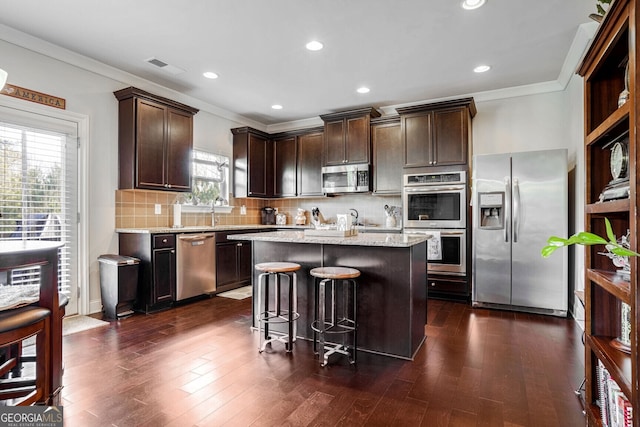 kitchen featuring a center island, tasteful backsplash, appliances with stainless steel finishes, crown molding, and dark hardwood / wood-style floors