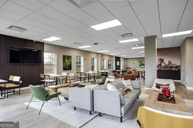 living room with a drop ceiling and light wood-type flooring