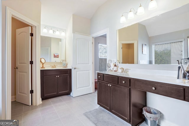 bathroom with vaulted ceiling, plenty of natural light, vanity, and tile patterned flooring