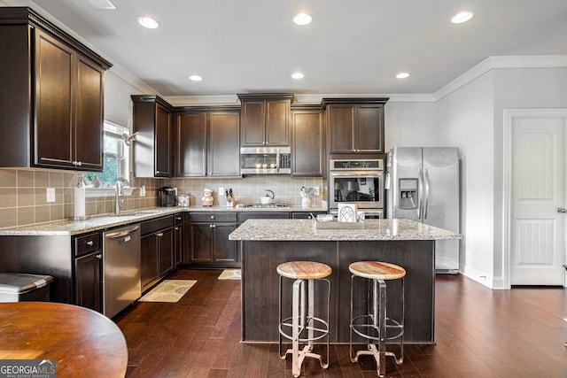 kitchen with a kitchen island, light stone countertops, appliances with stainless steel finishes, and dark hardwood / wood-style flooring