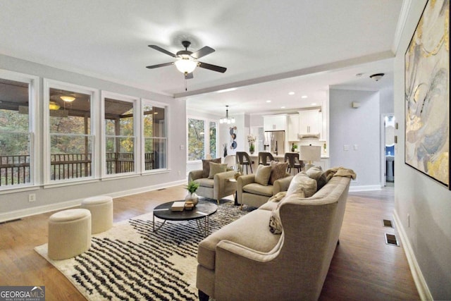 living room featuring ornamental molding, ceiling fan with notable chandelier, and light wood-type flooring