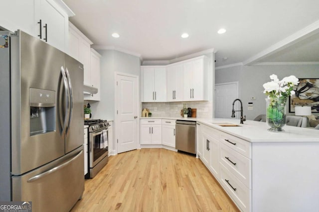 kitchen with sink, white cabinetry, light wood-type flooring, appliances with stainless steel finishes, and decorative backsplash