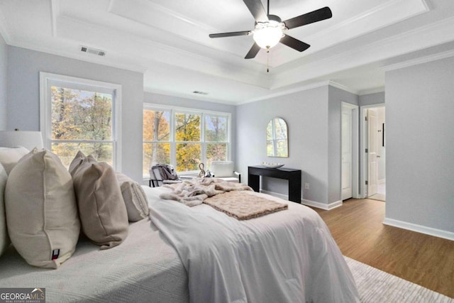 bedroom featuring crown molding, ceiling fan, a raised ceiling, and light hardwood / wood-style flooring