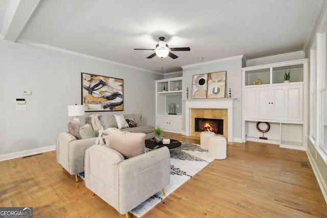 living room with a fireplace, ornamental molding, ceiling fan, and light wood-type flooring