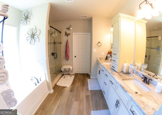 bathroom with wood-type flooring, shower with separate bathtub, and vanity