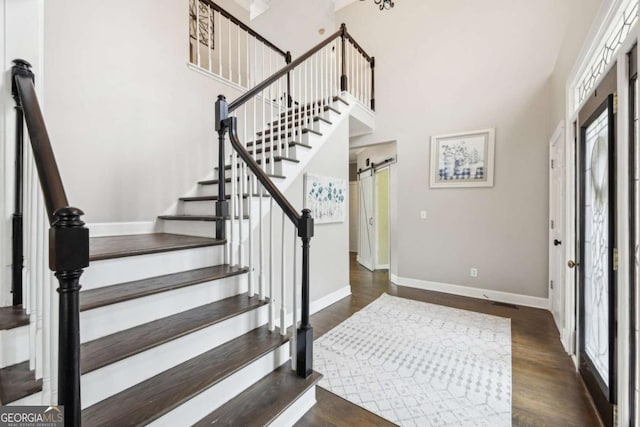 foyer with dark hardwood / wood-style flooring, a towering ceiling, and a barn door