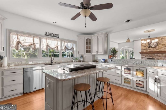 kitchen with sink, a breakfast bar area, hanging light fixtures, a center island, and stainless steel dishwasher