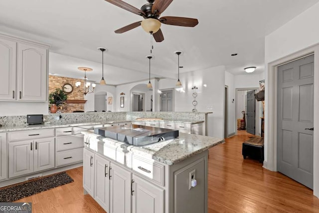 kitchen with pendant lighting, white cabinetry, a kitchen island, kitchen peninsula, and light wood-type flooring