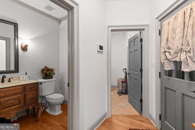 bathroom featuring vanity, hardwood / wood-style flooring, crown molding, and toilet