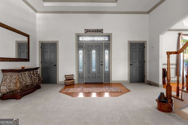 foyer entrance with crown molding, a tray ceiling, carpet floors, and a towering ceiling