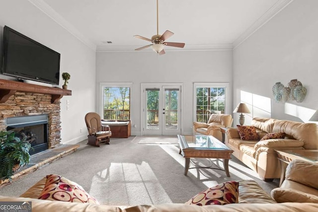 carpeted living room featuring crown molding, a stone fireplace, french doors, and a healthy amount of sunlight