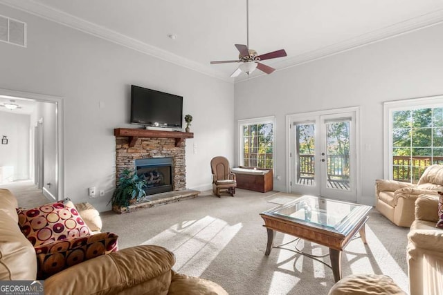 carpeted living room with ornamental molding, a stone fireplace, and a healthy amount of sunlight