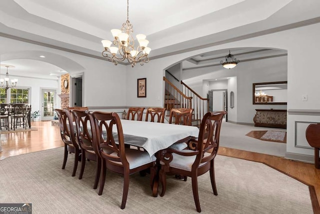 dining room featuring ornamental molding, light hardwood / wood-style floors, a chandelier, and a tray ceiling