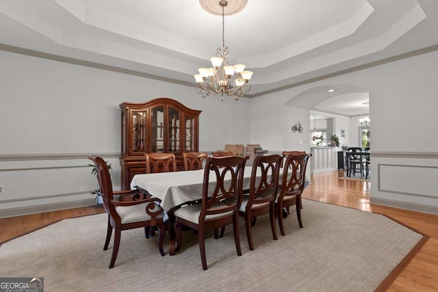 dining room featuring a tray ceiling, light hardwood / wood-style floors, and a chandelier