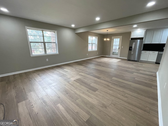 unfurnished living room featuring wood-type flooring and a chandelier