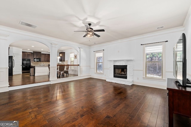 unfurnished living room with ornamental molding, dark hardwood / wood-style floors, a fireplace, and ceiling fan