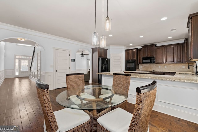 dining room featuring ceiling fan, ornamental molding, dark hardwood / wood-style flooring, and sink