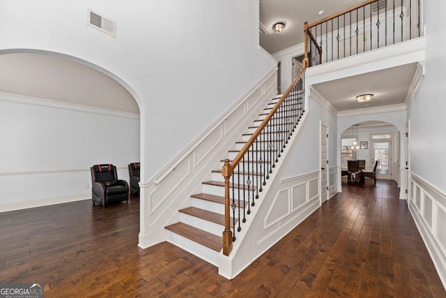 stairs featuring hardwood / wood-style flooring, crown molding, and a towering ceiling