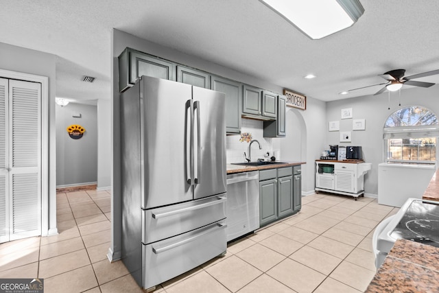 kitchen with appliances with stainless steel finishes, gray cabinets, sink, and light tile patterned floors