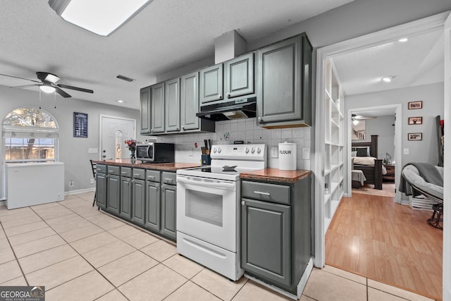 kitchen featuring light tile patterned floors, gray cabinets, ceiling fan, backsplash, and white electric stove