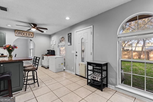 interior space with light tile patterned flooring, ceiling fan, and a textured ceiling