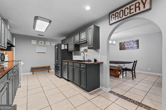 kitchen featuring gray cabinetry, sink, light tile patterned floors, and decorative backsplash