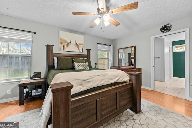 bedroom featuring ceiling fan, light hardwood / wood-style flooring, and a textured ceiling