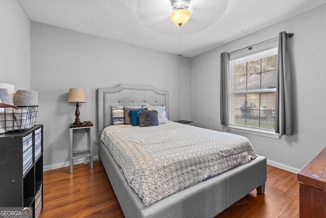 bedroom with hardwood / wood-style floors, a textured ceiling, and ceiling fan