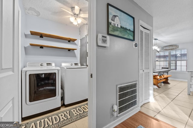 laundry room featuring heating unit, separate washer and dryer, a textured ceiling, and light tile patterned floors