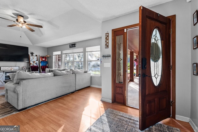 foyer featuring ceiling fan, lofted ceiling, a textured ceiling, and light hardwood / wood-style floors