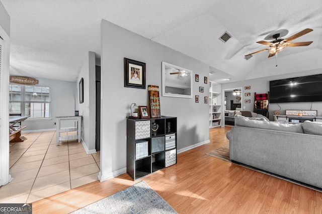 living room featuring light hardwood / wood-style floors, a textured ceiling, ceiling fan, and built in shelves