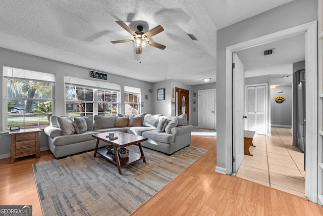 living room featuring ceiling fan, a textured ceiling, and light hardwood / wood-style floors