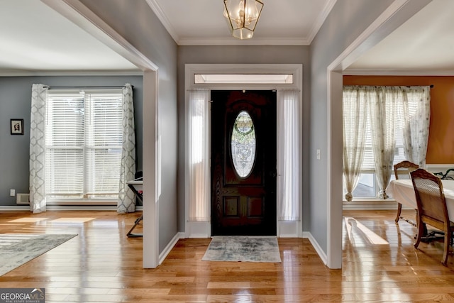 entrance foyer with an inviting chandelier, crown molding, and light hardwood / wood-style flooring