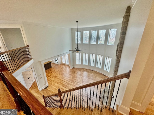 stairs with hardwood / wood-style floors, a towering ceiling, and ceiling fan