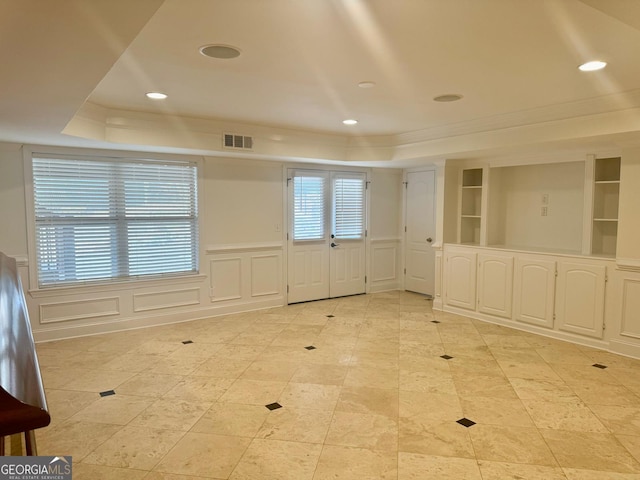 unfurnished room with crown molding, a raised ceiling, and built in shelves