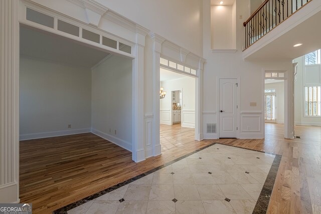 unfurnished living room with a stone fireplace, a wealth of natural light, ceiling fan, and light hardwood / wood-style flooring