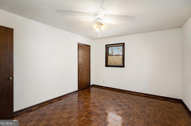 empty room featuring ceiling fan, dark parquet floors, and a textured ceiling