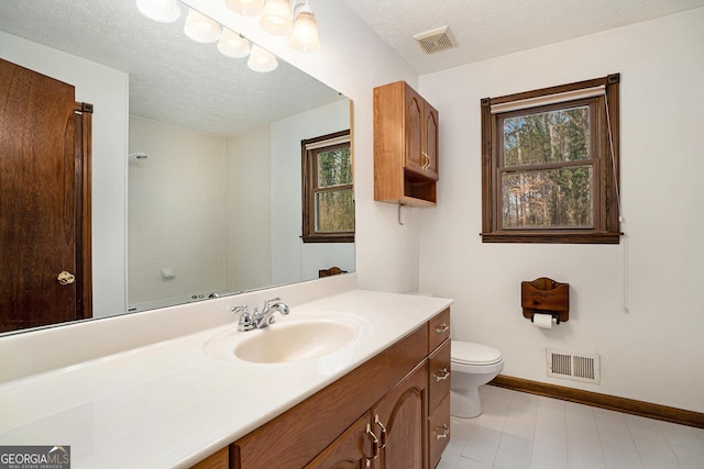 bathroom featuring plenty of natural light, toilet, vanity, and a textured ceiling