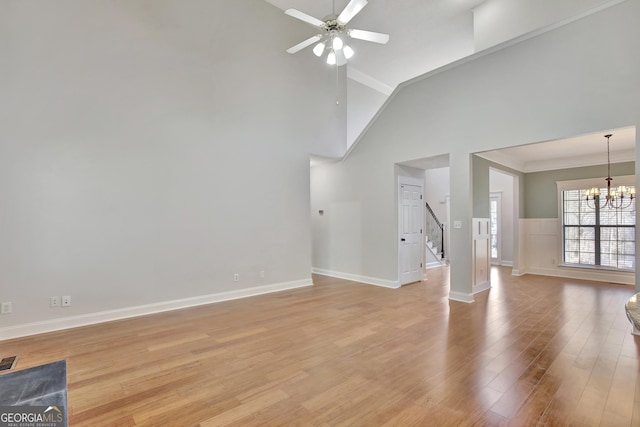 unfurnished living room featuring ornamental molding, ceiling fan with notable chandelier, high vaulted ceiling, and light hardwood / wood-style flooring