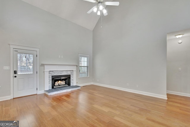 unfurnished living room with high vaulted ceiling, a fireplace, light hardwood / wood-style floors, and ceiling fan